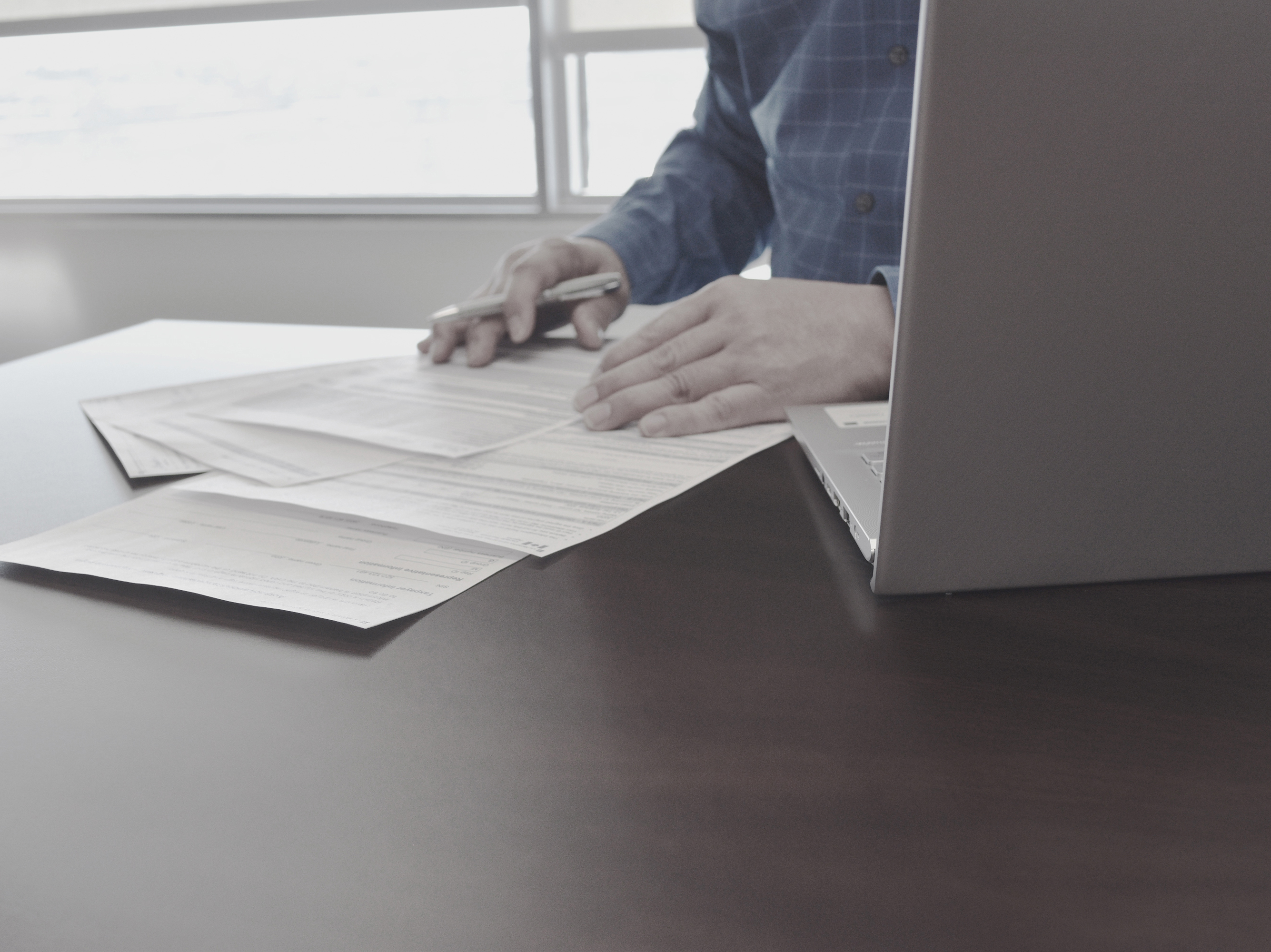 Professional tax preparer sitting at a desk, holding a pen and reading through tax documents